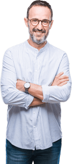 A friendly male employee smiling. He is middle-aged, greying, has a button-up pin-striped shirt rolled to the forearms, a watch, jeans, and his arms are crossed in a friendly manner.